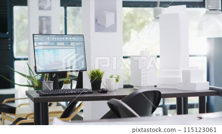 Designing office has empty desk with computer operating cad, production layouts and blueprints on the design table. Architectural work environment fitted with latest modeling appliances. Designing office has empty desk with computer operating cad, production layouts and blueprints on the design table. Architectural work environment fitted with latest modeling appliances. 115123061