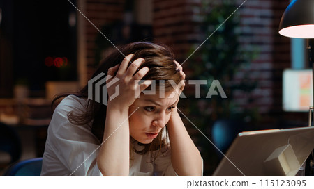 Worker frustrated by mistake she made while inputting data on laptop while working on company project overnight. Close up shot of upset businesswoman realizing error she made 115123095