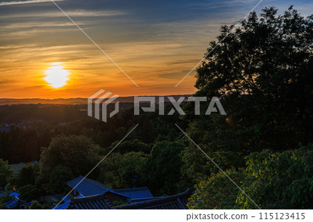 Evening view from Nigatsudo Hall of Todaiji Temple in the ancient city of Nara. The setting sun shines above the Ikoma mountain range, covered by thin golden clouds. 115123415