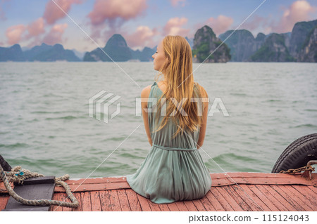 Attractive woman in a dress is traveling by boat in Halong Bay. Vietnam. Travel to Asia, happiness emotion, summer holiday concept. Picturesque sea landscape. Ha Long Bay, Vietnam 115124043