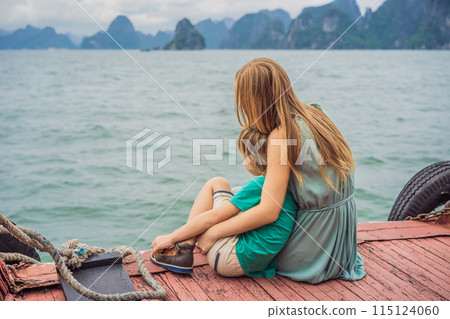 Mom and son travelers is traveling by boat in Halong Bay. Vietnam. Travel to Asia, happiness emotion, summer holiday concept. Traveling with children concept. After COVID 19. Picturesque sea landscape Mom and son travelers is traveling by boat in Halong Bay. Vietnam. Travel to Asia, happiness emotion, summer holiday concept. Traveling with children concept. After COVID 19. Picturesque sea landscape 115124060