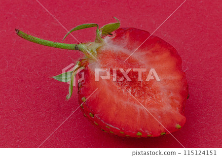 Cut ripe strawberry on red background macro shot 115124151