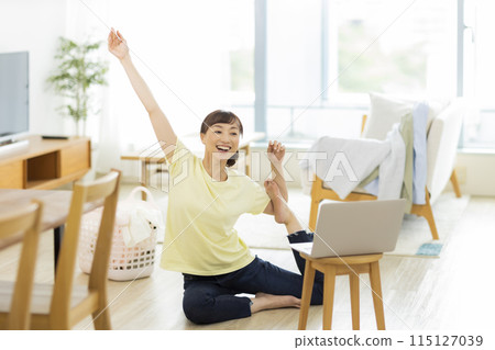 A woman stretching while looking at a computer A woman stretching while looking at a computer 115127039