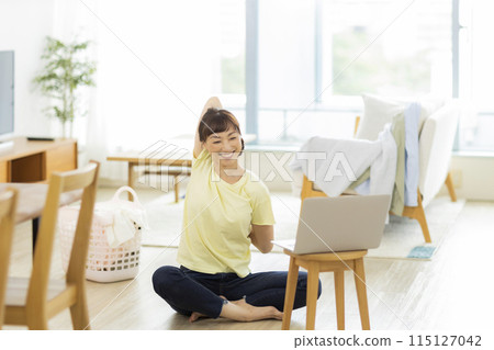 一位女士一邊看電腦一邊伸展身體 一位女士一邊看電腦一邊伸展身體 115127042