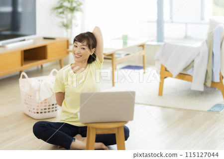 A woman stretching while looking at a computer 115127044