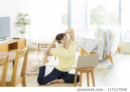 A woman stretching while looking at a computer 115127048