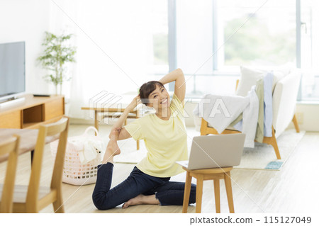 A woman stretching while looking at a computer 115127049