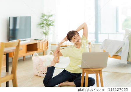 一位女士一邊看電腦一邊伸展身體 115127065