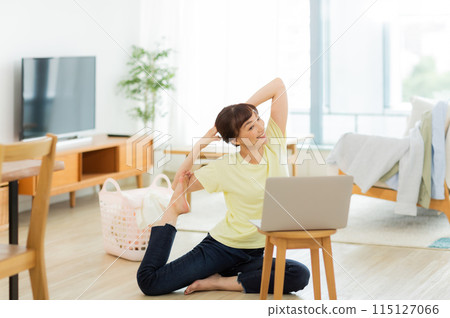 一位女士一邊看電腦一邊伸展身體 115127066