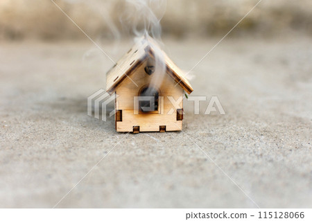 a toy wooden house is smoking. fire, disaster 115128066