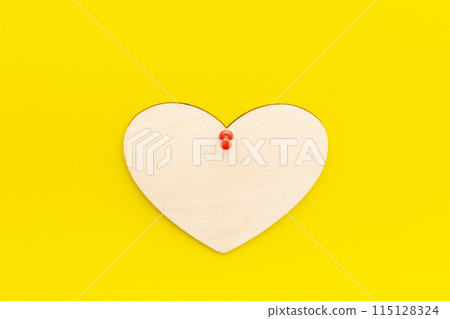 wooden heart on a yellow background pinned with a button wooden heart on a yellow background pinned with a button 115128324