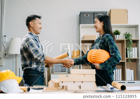 Construction team shake hands greeting start new project plan behind yellow helmet on desk in office center to consults about their building project.. 115128955