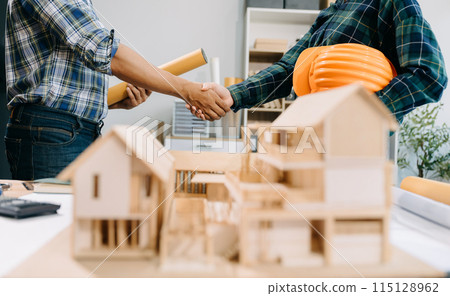 Construction team shake hands greeting start new project plan behind yellow helmet on desk in office center to consults about their building project.. 115128962