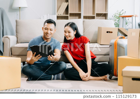 Asian young attractive couple man and woman use tablet and smartphone online shopping furniture decorate house with carton package move in new house. married asian moving home. . Asian young attractive couple man and woman use tablet and smartphone online shopping furniture decorate house with carton package move in new house. married asian moving home. . 115129173