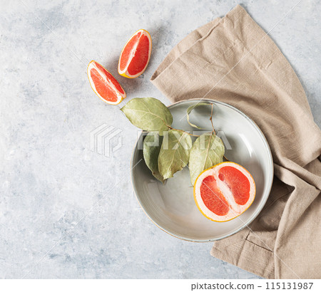 juicy red grapefruit in a plate and slices on a blue background with a light napkin.  juicy red grapefruit in a plate and slices on a blue background with a light napkin.  115131987
