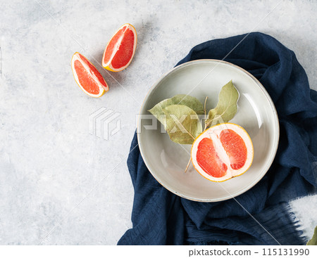 juicy red grapefruit in a plate and slices on a blue background with a dark napkin.  115131990