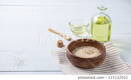 Natural vegetable oil from sesame seeds in a clear bottle on the wooden background. Natural vegetable oil from sesame seeds in a clear bottle on the wooden background. 115132032