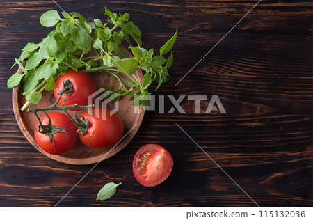 Healthy  food. Fresh aromatic basil and tomato on wood plate on a brown wooden background Healthy  food. Fresh aromatic basil and tomato on wood plate on a brown wooden background 115132036