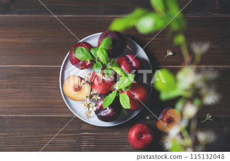 a few juicy red plums in blue plate with branch blossom flowers on a napkin a few juicy red plums in blue plate with branch blossom flowers on a napkin 115132048