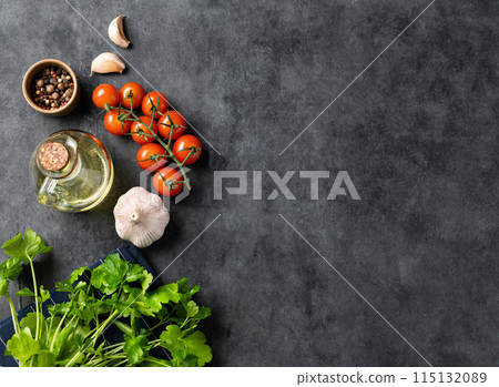 Spices and fresh herbs parsley, garlic, pepper, tomatoes and oil on a dark gray background.  115132089
