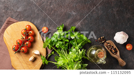 Spices and fresh herbs parsley, garlic, pepper, tomatoes and oil on a dark brown background.  115132095