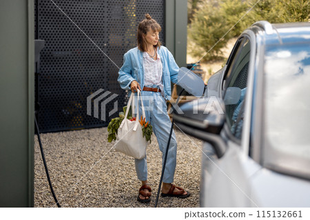 Woman plugging a charger into electric vehicle Woman plugging a charger into electric vehicle 115132661