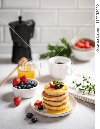 Homemade classic American pancakes in a stack with fresh berries, honey, cup of coffee and black pot 115132690
