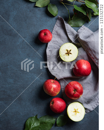 Juicy red apples with leaves on a gray napkin on a dark blue background.  115132722
