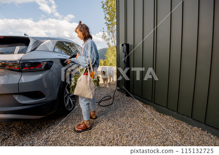 Woman plugging a charger into electric vehicle 115132725