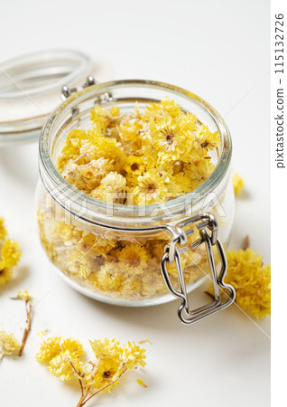 Helichrysum italicum. Yellow dried herb  flowers in a jar close-up on a white background 115132726