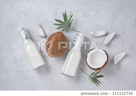 Healthy flat lay concept. Vegan milk bottles, coconut slices and palm branch on gray background 115132738