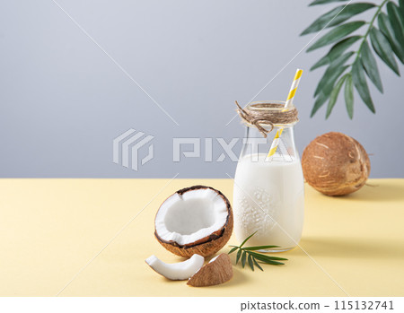 Concept Of Conscious Consumption. Vegan milk bottle with half coconuts and palm branch  115132741