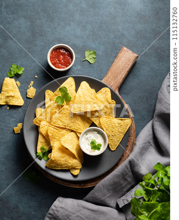 Tradition Mexican food. Corn chips nachos with salsa and cheese sauce and fresh herb on gray plate Tradition Mexican food. Corn chips nachos with salsa and cheese sauce and fresh herb on gray plate 115132760