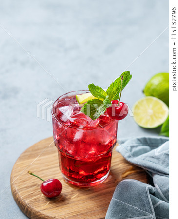 Cherry-lime mojito cocktail with mint, lime and ice on a wooden board on a light background Cherry-lime mojito cocktail with mint, lime and ice on a wooden board on a light background 115132796
