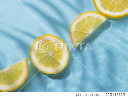 Lemon slices in water on a blue background with shadow and waves close up. 115132815