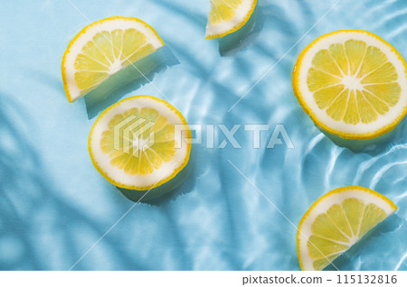 Lemon slices in water on a blue background with shadow and waves close up. 115132816