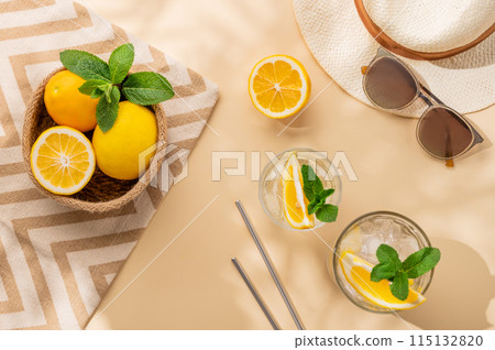 Summer layout with lemonade, fresh citrus fruits, hat and sunglasses on a beach towel Summer layout with lemonade, fresh citrus fruits, hat and sunglasses on a beach towel 115132820
