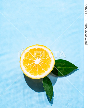 Lemon slice with leaves in water on a blue background with shadow and waves. 115132822