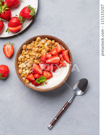 Natural yogurt with granola and strawberries in a wooden bowl on a blue background  115133207
