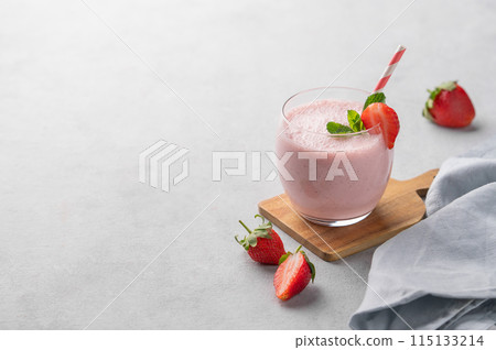 A glass of fresh strawberry smoothie with mint on a wooden board on a light background A glass of fresh strawberry smoothie with mint on a wooden board on a light background 115133214