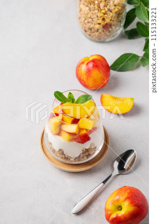 Flat lay of greek yogurt parfait with peach and muesli in a glass on a light background with fruits Flat lay of greek yogurt parfait with peach and muesli in a glass on a light background with fruits 115133221