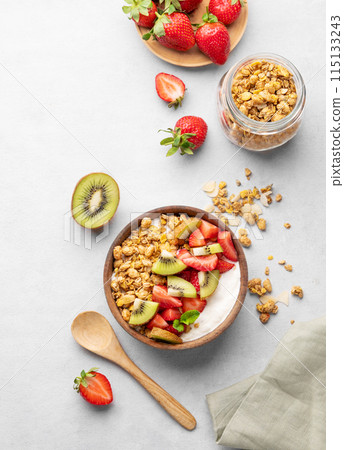 Natural yogurt with granola, kiwi and strawberries in a wooden bowl on a light background Natural yogurt with granola, kiwi and strawberries in a wooden bowl on a light background 115133243