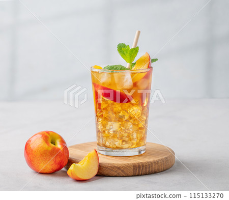Refreshing peach iced mint tea. The concept of a healthy homemade cold summer drink in a tall glass 115133270