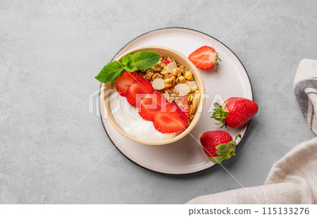 Natural yogurt with muesli and strawberries in a bowl on a blue background with fresh berries Natural yogurt with muesli and strawberries in a bowl on a blue background with fresh berries 115133276