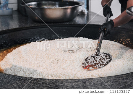 hands of a male cook cooking traditional oriental Uzbek rice pilaf in a cauldron. Central Asian Pilaf Center in Uzbekistan hands of a male cook cooking traditional oriental Uzbek rice pilaf in a cauldron. Central Asian Pilaf Center in Uzbekistan 115135337