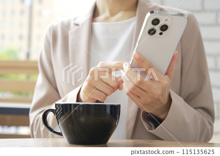 Businesswoman using smartphone in cafe, no face Businesswoman using smartphone in cafe, no face 115135625