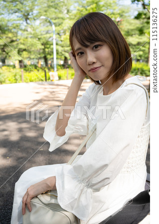 一名婦女坐一條室外長凳 一名婦女坐一條室外長凳 115136275