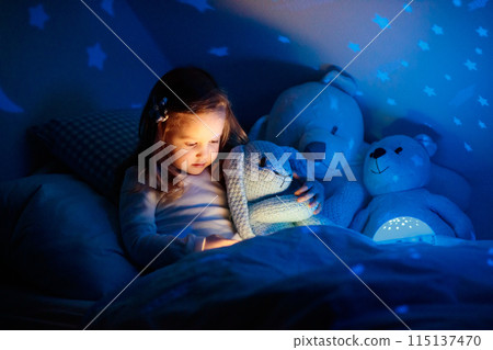 Little girl reading a book in bed 115137470