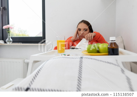 A young teenager lies on a bed and takes out handkerchiefs to blow her nose. 115138507