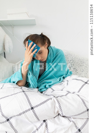 The teenager puts cold compresses on her head to reduce the high temperature. The teenager puts cold compresses on her head to reduce the high temperature. 115138654